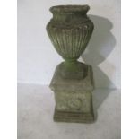 A weathered garden urn on plinth