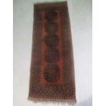 An Eastern hand woven red ground runner, 171cm x 64cm