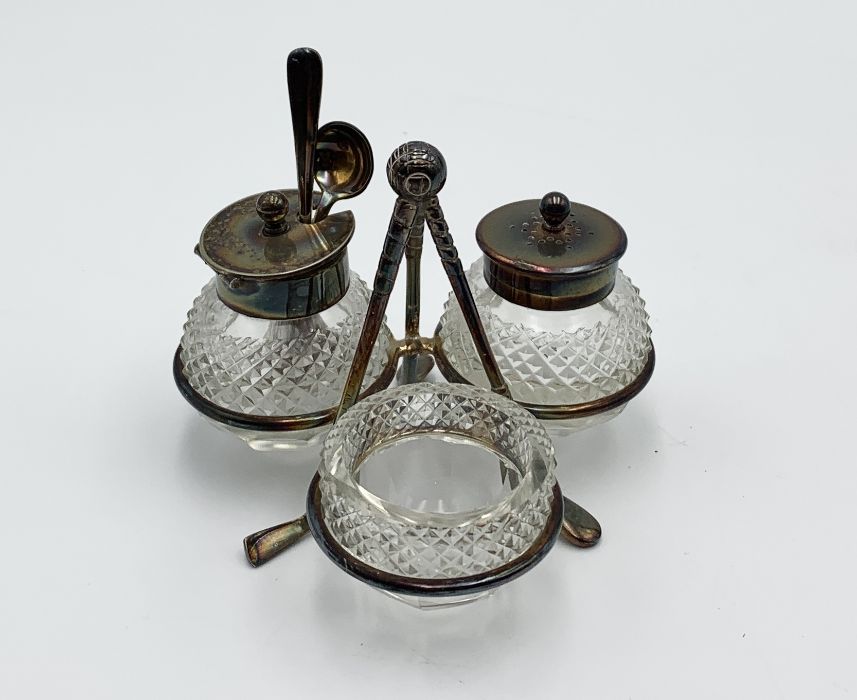 A silver plated condiment set on golf club supports with golf ball finial