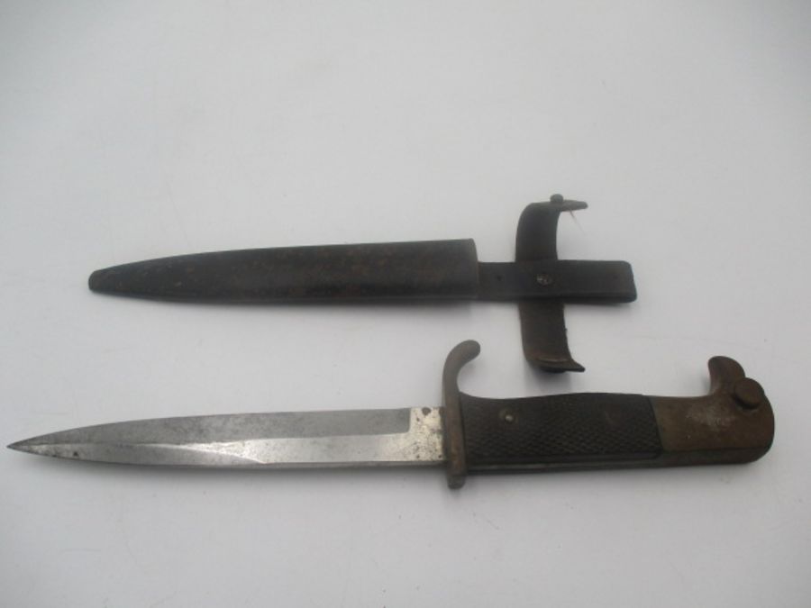 A German WWII dagger with eagle head handle over black chequered grip in metal scabbard