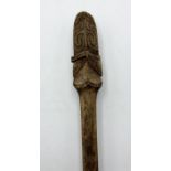 A wooden war club with carved tongue-shaped tip with ornate facial tattoo-style carved decoration,