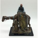 A spelter Bergman style figure of a carpet seller on a camel. A/F