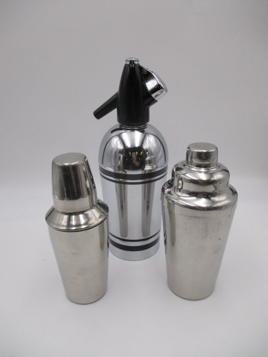 A Sparklets soda siphon, along with two chrome cocktail shakers