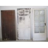 Three doors, a wooden door, a painted wooden panel door and a wooden door with eight glass panels.