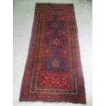 An Eastern hand woven red ground rug, 260cm x 116cm