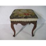 An antique footstool on cabriole legs