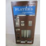 A vintage Player's cigarette vending machine with various empty cigarette packets