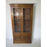 An oak display cabinet with leaded light detailing and cupboard under