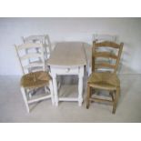 A white painted pine drop leaf table with drawers at both ends, along with four dining chairs (two
