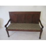 An antique oak settle with upholstered seat
