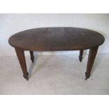An Edwardian inlaid oval extending dining table with one leaf on square tapered legs