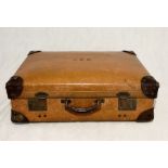 A vintage tan leather suitcase with brass double locks