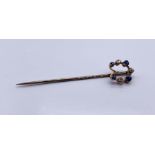 An unmarked gold tie pin set with diamonds and sapphires