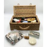 A wicker basket containing a quantity of sewing related items, books, buttons etc.