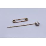 A 9 ct gold tie pin set with a seed pearl along with a gold coloured pin