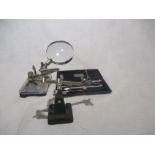 A collection of drawing instruments with a desk top clip on magnification tool, etc.