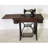 A Singer oak cased sewing table, containing an Egyptian model sewing machine, raised on a cast
