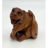 A carved wooden Netsuke in the form of a tiger