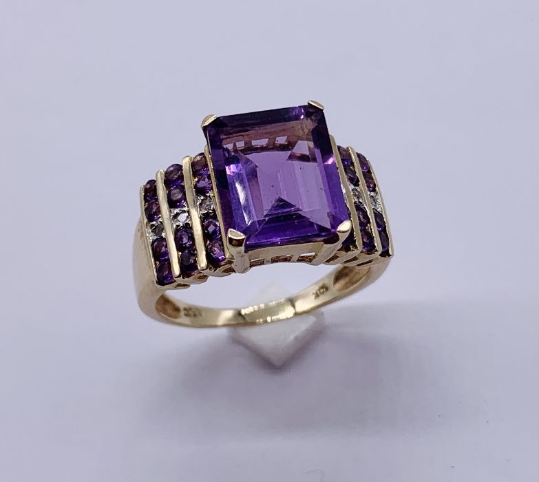 A large 10ct gold ring set with a central amethyst with diamond and amethyst shoulders