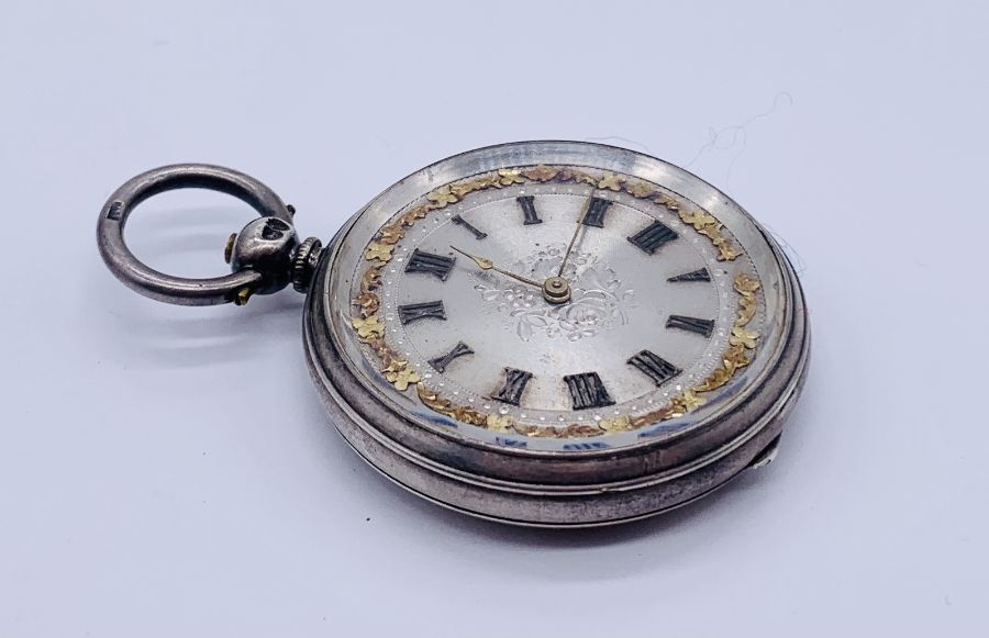 A hallmarked silver fob watch with silvered dial with gold detailing