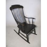 An ebonised & gilded rocking chair with foliage decoration to top