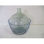 A large glass carboy in wirework basket