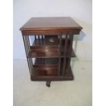 Late Victorian mahogany revolving bookcase on cruciform base with castors, the central pillar