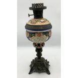 An early 20th century brass and painted ceramic oil lamp, having painted cherub and floral design