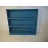 A freestanding blue painted bookcase.