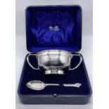 A cased Arts & Crafts hallmarked silver two handled bowl and matching spoon, hallmarked for Barker