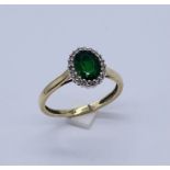 An emerald and diamond cluster ring set in 9ct gold