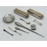 A collection of hallmarked silver items including a dish, brushes, silver handled button hooks etc.