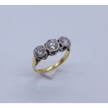 A diamond three stone ring set in 18ct gold, illusion set, the centre diamond appears to measure