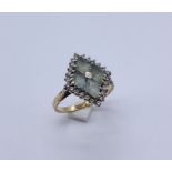 A 9ct gold dress ring set with pale green stones surrounded by diamonds