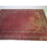 A red ground rug of traditional form. Includes an area of staining as pictured. 287cm x 199cm