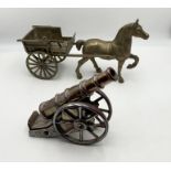 A small iridescent iron canon along with a brass horse and carriage