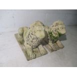 A pair of recumbent reconstituted stone lions, length 40cm