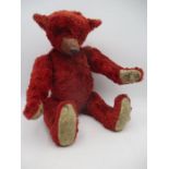 A red straw filled teddy bear with jointed limbs, height approx 39cm