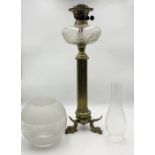 A Victorian brass oil lamp on column base with stylised dolphin feet and frosted shade
