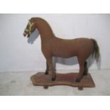 An antique pull along horse on wooden base with metal wheels, approx 70cm length