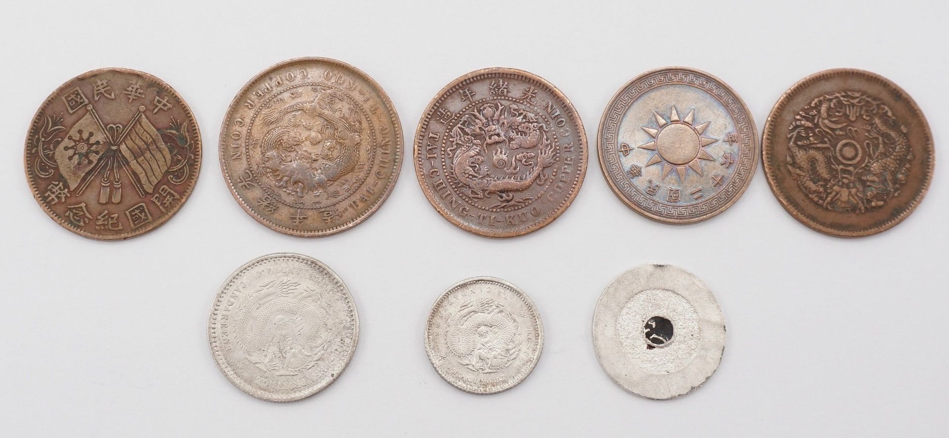 Sieben chinesische Münzen und ein Jeton