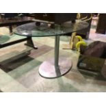 A ellipse shaped glass topped table. Light scratches to glass. W:140cm x D:80cm x H:73.5cm