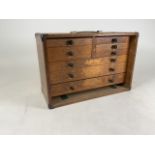A stained oak watch makers eight draw cabinet with an assortment of tools. Stamped M&W. W:51cm x