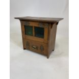 A Liberty's & Co style small hanging arts and crafts three drawer cabinet with green glass oak