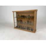 A pine glass front display case with two shelves, contains a collection of brass and copper