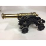A fireside brass and cast iron model canon with stylised dragon supports. W:45cm x D:16cm x H: