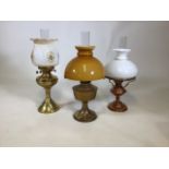 Three brass lamps with glass shades.