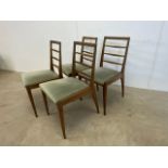 A set of four teak mid century ladder back dining chairs with green upholstered seats in the style