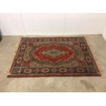 A Persian style rug, red ground with central stylised medallion. W:140cm x D:cm x H:197cm W: