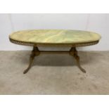 An retro onyx ellipse shaped coffee table on a gilt metal base, with gilt metal detail to sides.